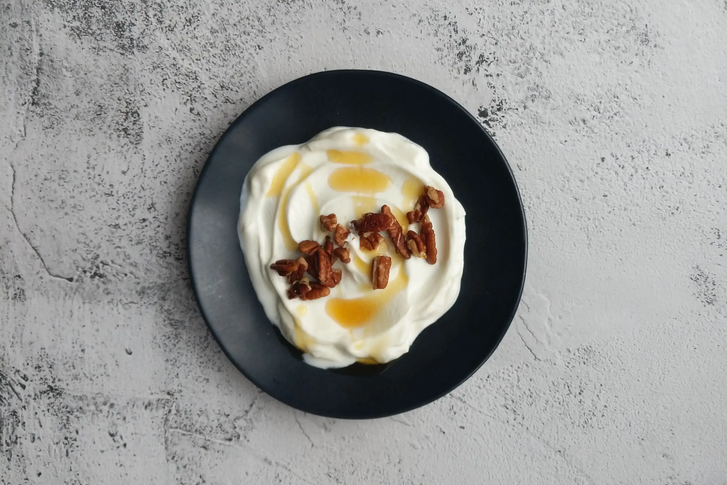 a bowl of yogurt with pecans and honey